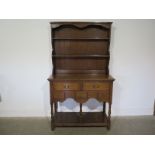 A reproduction oak dresser, plate rack over two long drawers above three short,