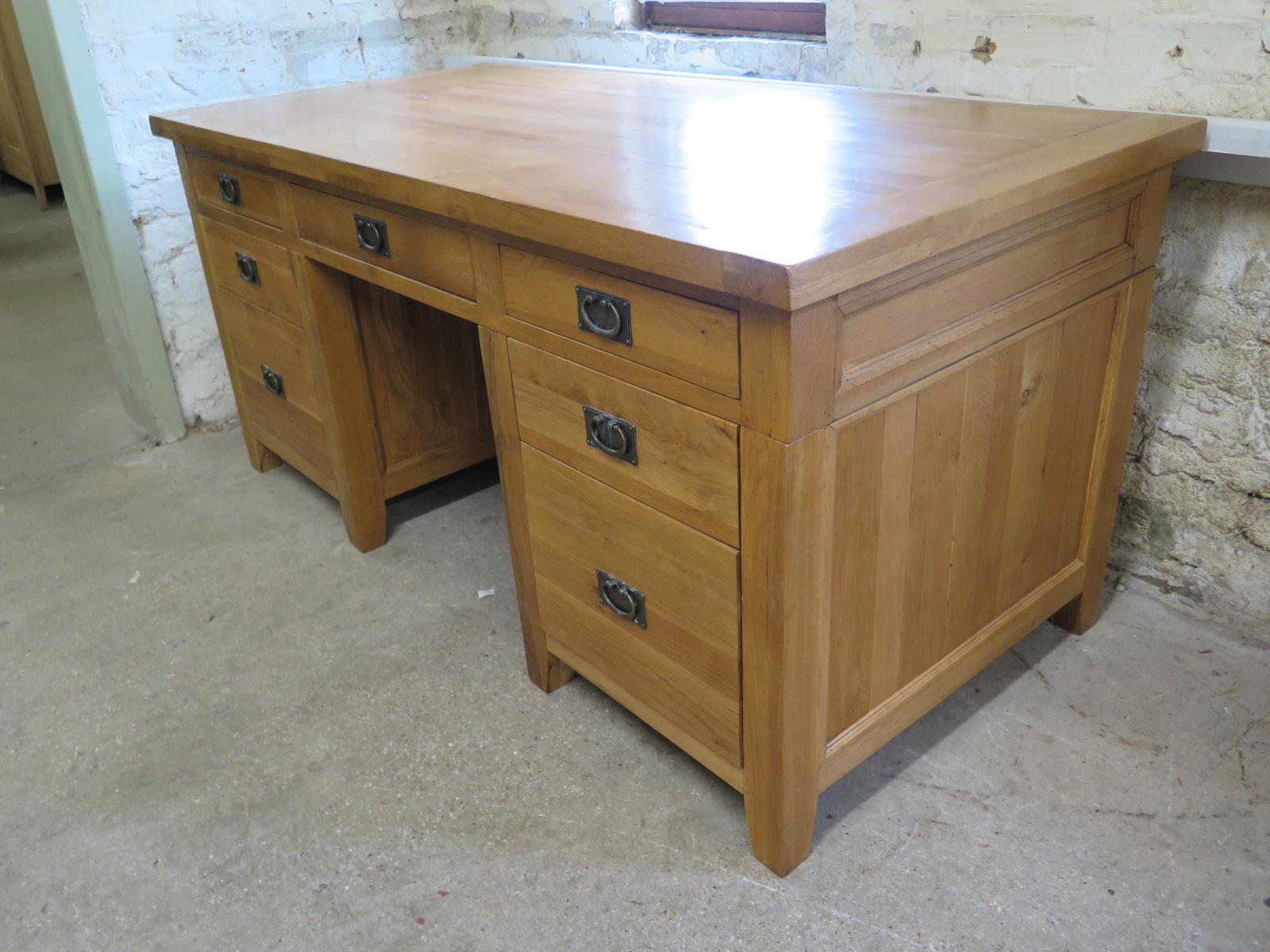 An oak twin pedestal desk with an arrangement of seven drawers - Height 84cm x 180cm x 86cm