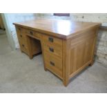 An oak twin pedestal desk with an arrangement of seven drawers - Height 84cm x 180cm x 86cm