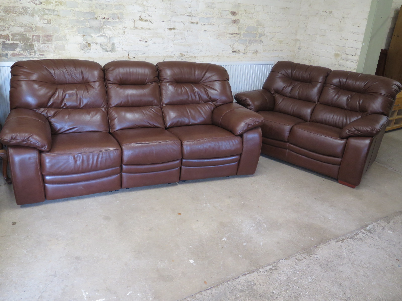 A brown leather two seater sofa and a three seater sofa with end recliners,
