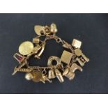 A 9ct yellow gold charm bracelet with 22 charms - approx weight 30 grams - in clean condition