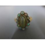 An 18ct yellow gold dress ring with central oval cats eye agate surrounded by opals - size Q -