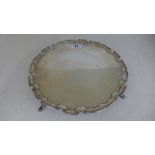 A silver hallmarked salver with pie crust boarder raised on four pad feet marked for London 1908/09