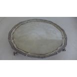 A silver hallmarked salver with ribbed edge and piecrust boarder raised on four ball and claw feet