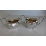 Two silver hallmarked items in the form of a milk jug and sugar bowl,