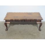 A walnut coffee table with a shaped top on ball and claw feet - Height 37cm x 106cm x 52cm
