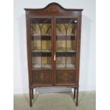 A Edwardian mahogany twin door display cabinet with twin glazed doors over inlaid panels raised on