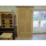 A Victorian stripped pine single door cupboard with a shelved interior above a drawer missing part