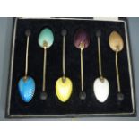 A set of six silver gilt handled coffee bean spoons with alternative enamel decoration to the back