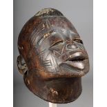 A Makonde helmet mask Mozambique with a small raised mound of hair with incised scarifications and