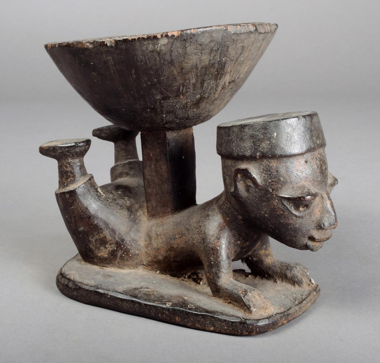 A Yoruba divination bowl Nigeria with an incised edge and supported by an acrobatic figure 14.5cm