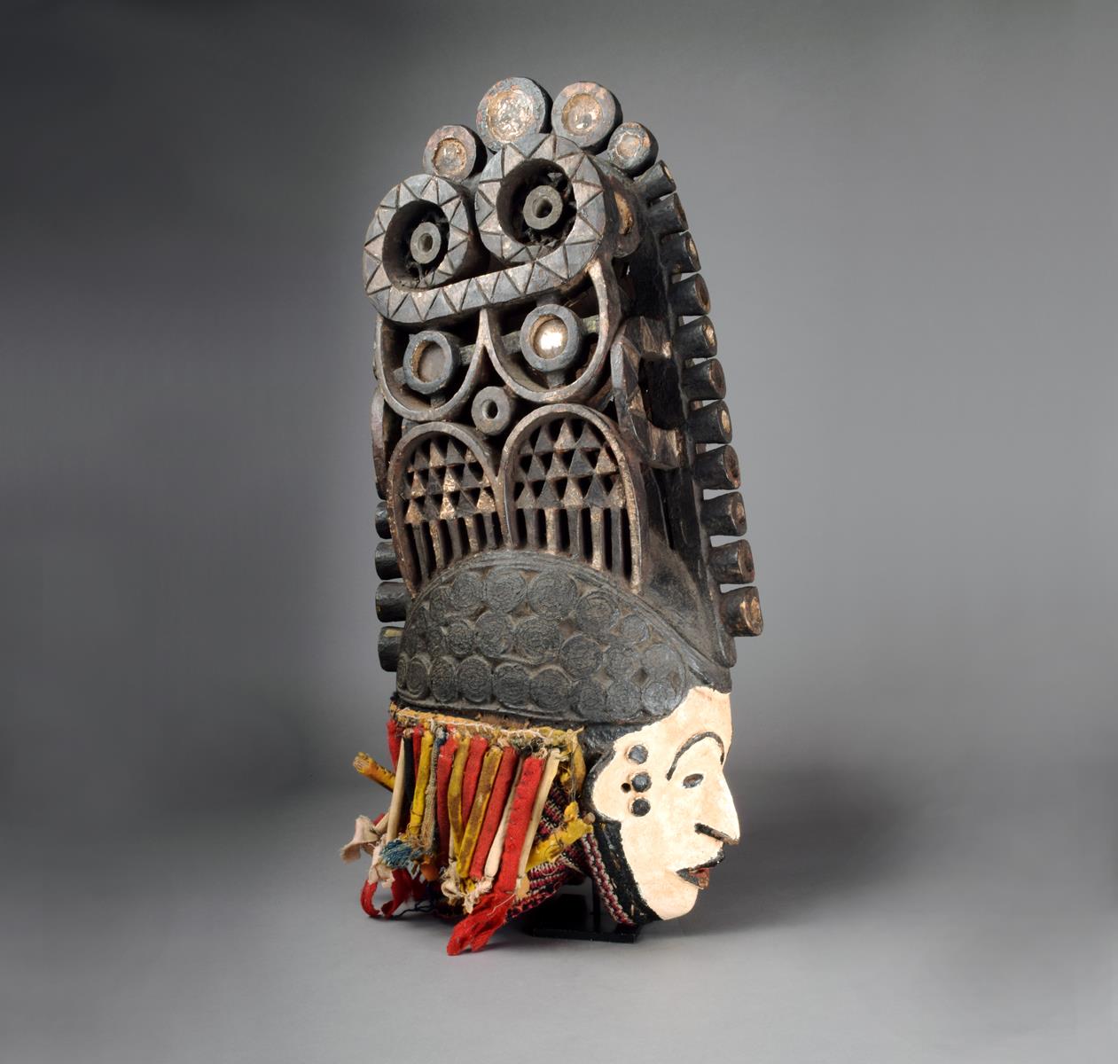 An Igbo spirit mask Nigeria with a white painted face and tight curled coiffure with a large