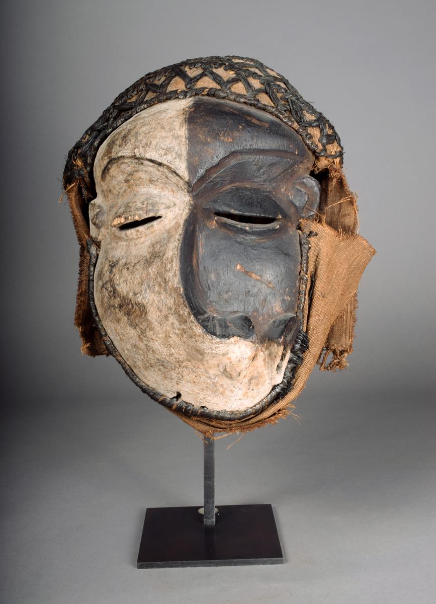 A Pende sickness mask D.R.Congo with a distorted face and with white and black pigment with fibre