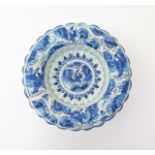 A Delft lobed dish  c.1700, painted in blue with a central seated figure within a stylized border of