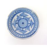A delftware charger  early 18th century, decorated in blue with a central swirl within stylized