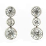A pair of diamond drop earrings, each white gold earring is set with three graduated old circular