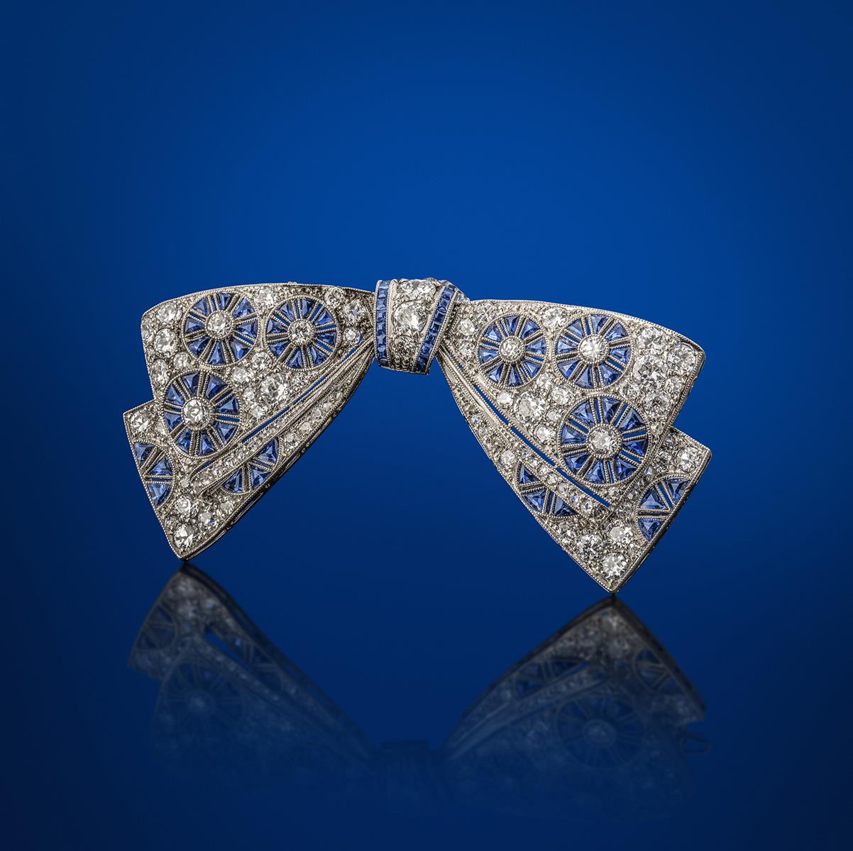 An early Art Deco bow brooch, with calibré-cut sapphire-set circular motifs with diamond centres, on