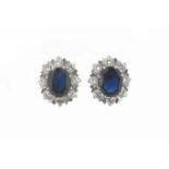 A pair of sapphire and diamond cluster earrings, the oval shaped sapphires are set within a surround