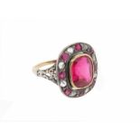 A synthetic ruby cluster ring, the cushion-shaped synthetic ruby is set within a surround of