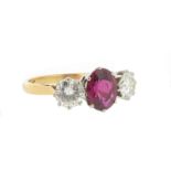 A ruby and diamond three stone ring, the oval shaped ruby is set with two round brilliant cut