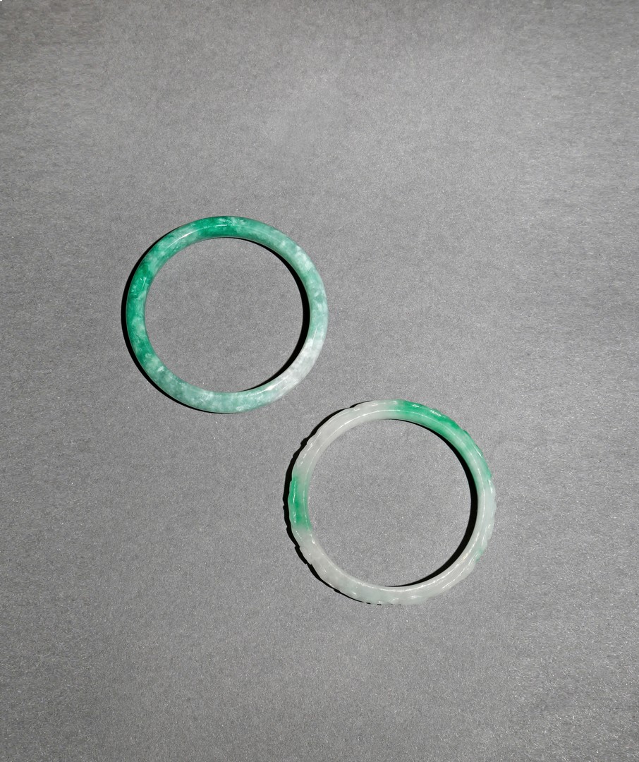 TWO CHINESE JADEITE BANGLES, 20TH CENTURY One plain, the other carved with bats amongst fruiting and