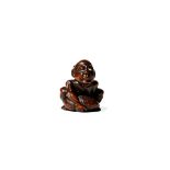 † A JAPANESE WOOD AND IVORY NETSUKE, 19TH CENTURY Carved as a blind masseur holding a