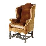 An early 18th century wing armchair, with an arched back and scroll arms, upholstered with later