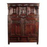 A Queen Anne oak press cupboard, the frieze carved with vine leaf and grapes and with triad initials