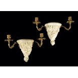 A pair of continental biscuit porcelain and gilt metal wall lights, decorated with scrolling