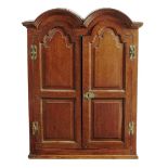 A mid 18th century oak cupboard, the double domed top above a pair of fielded panel doors