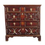 A late 17th century oak chest, of four long drawers each with geometric panelled fronts and with