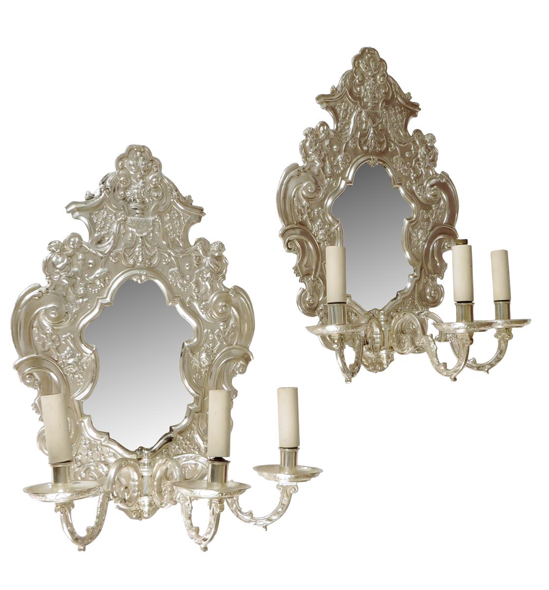 A pair of Baroque style silvered metal girandoles, each with a shaped plate within a scroll cast