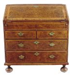 An early 18th century burr walnut bureau, cross and feather banded, the hinged fall revealing an