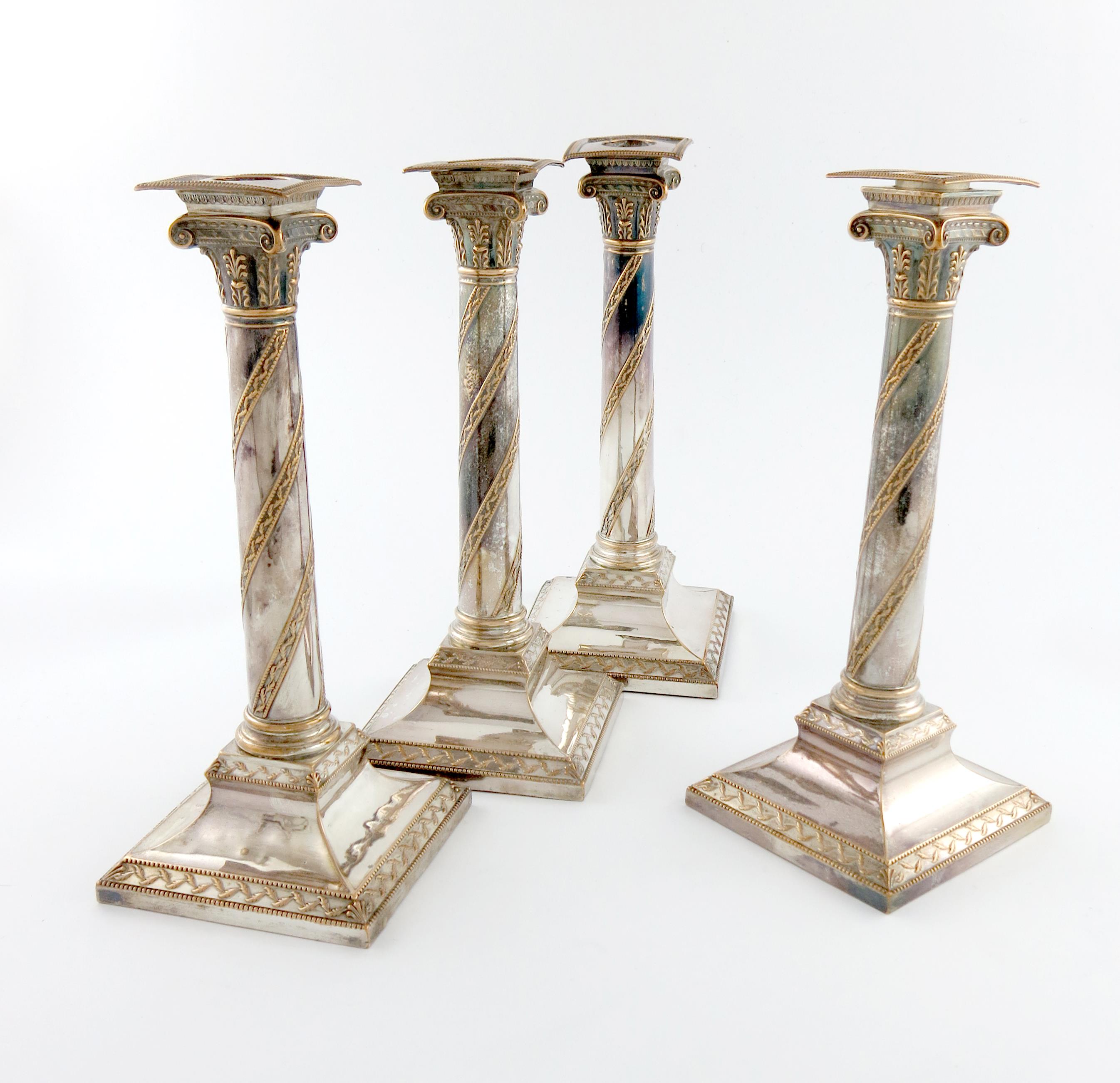 A set of four George III old Sheffield plated candlesticks, circa 1790, the columns with swirl