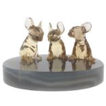 A group of three carved smoky quartz seated French bulldog puppies, on an oval agate plinth. The