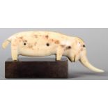 λ An Inuit mammoth walrus ivory with inset baleen eyes and decoration, 12.5cm long, on a stand. (2)