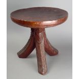An Igbo stool Nigeria carved wood, with a circular top and tripod legs, with a red stain, 33cm