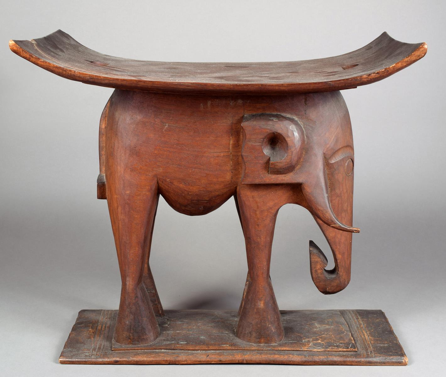 An Ashanti stool Ghana wood, with a carved elephant support, 50.5cm high, 56cm long.