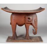 An Ashanti stool Ghana wood, with a carved elephant support, 50.5cm high, 56cm long.