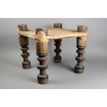 A North African stool wood, with polychromed turned wood legs and with a hide covered seat, 34cm