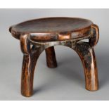 A Hehe stool Tanzania wood, with a glossy patina to the top, on three scroll legs, with pierced top,