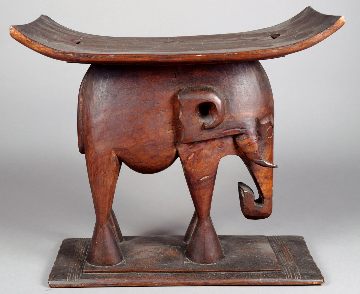 An Ashanti stool Ghana wood, with a carved elephant support, 50.5cm high, 54.5cm long.