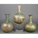 Three Roman glass bottles 1st - 2nd century AD, with globular bodies and long necks, two with folded