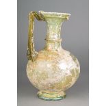 A Roman glass jug circa 3rd - 4th century AD pale green and raised on a spreading foot with a