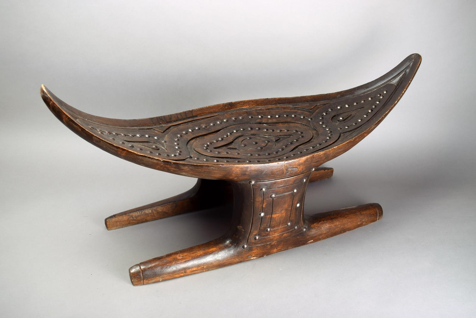 A Surinam Maroons stool South America wood, with metal stud decoration, with a curved eliptical