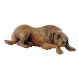 A late 19th century Black Forest carved wood model of a recumbent mountain dog, with glass eyes,