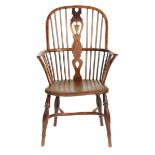 An early 19th century yew highback Windsor armchair, with a pierced splat back centered a shield,