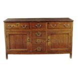 A George III oak dresser, with three frieze drawers above a pair of panelled cupboard doors and a