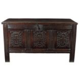 A late 17th century oak coffer, the hinged lid revealing a lidded till, the triple panelled front