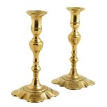 A pair of George II brass candlesticks, each with a knopped stem and stylised petal bases, 22.7cm